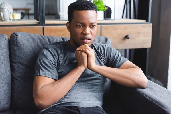 Trauriger nachdenklicher afrikanisch-amerikanischer Mann sitzt zu Hause auf Sofa — Stockfoto