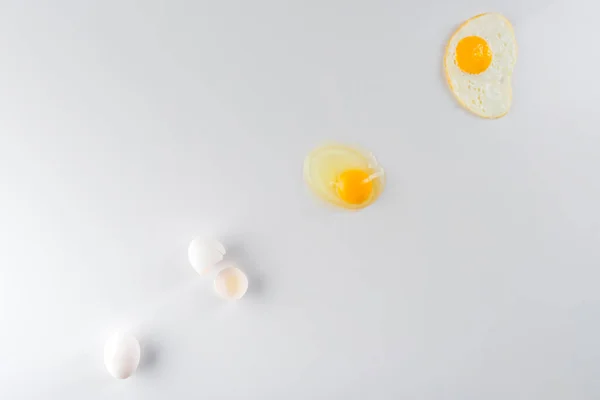 Top view of eggs transformation phases from raw to fried on white — Stock Photo