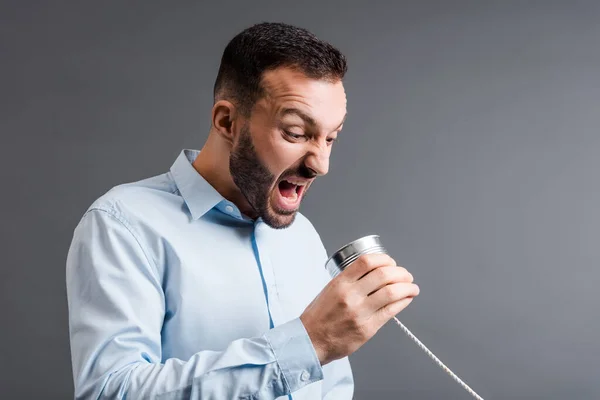 Homem zangado gritando enquanto segurando lata isolada em cinza — Fotografia de Stock