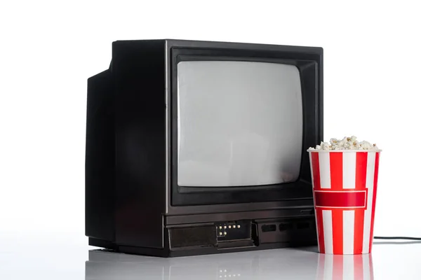 Eimer mit Popcorn in der Nähe von Vintage-Fernseher auf weiß, Evolution-Konzept — Stockfoto