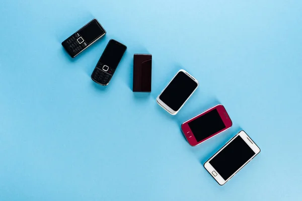 Top view of vintage mobile phones and modern smartphones on blue, evolution concept — Stock Photo