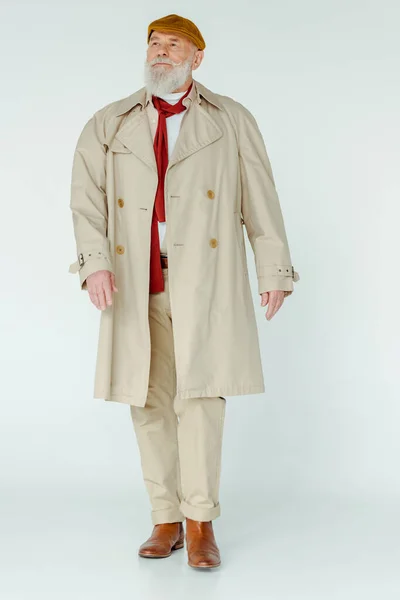 Piena lunghezza di elegante uomo anziano in trench guardando lontano su sfondo bianco — Foto stock