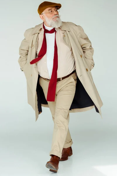 Comprimento total de homem sênior bonito em casaco de trincheira andando sobre fundo branco — Fotografia de Stock