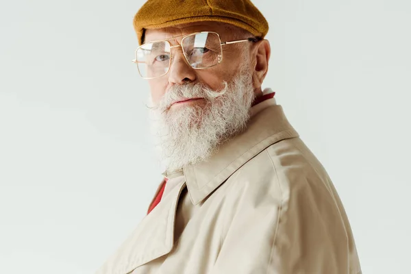 Seitenansicht eines modischen älteren Mannes mit Sonnenbrille und Mantel, der isoliert auf weiß in die Kamera blickt — Stockfoto