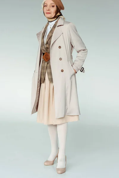 Volle Länge der eleganten älteren Frau im Mantel, die in die Kamera auf weißem Hintergrund blickt — Stockfoto
