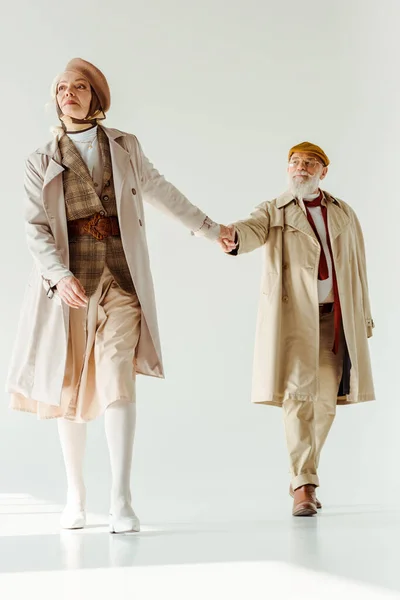 Full length of stylish senior woman holding hand of handsome man on white background — Stock Photo
