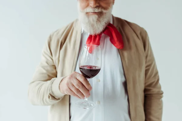 Vista recortada de un hombre mayor elegante sosteniendo un vaso de vino tinto aislado en blanco - foto de stock