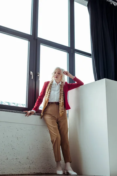 Full length of elegant senior woman standing near window in photo studio — Stock Photo