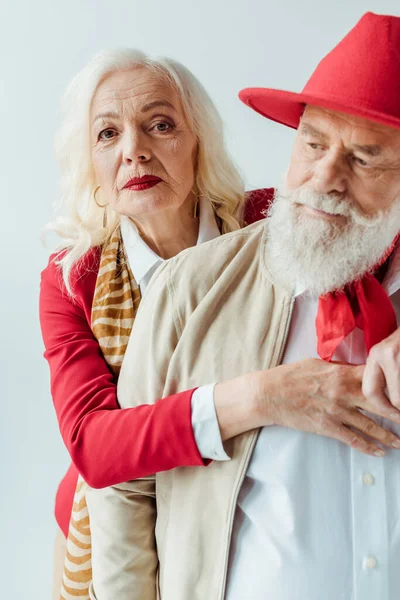 Focus selettivo di elegante donna anziana abbracciando bell'uomo in cappello rosso isolato su bianco — Foto stock