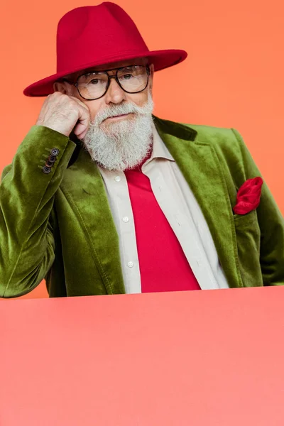 Un vieil homme à la mode vêtu d'une veste et de lunettes regardant une caméra isolée sur un corail — Photo de stock