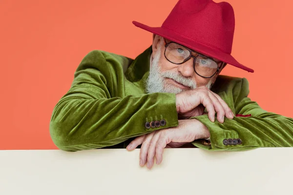 Stylish senior man in jacket and eyeglasses looking at camera on white background isolated on coral — Stock Photo