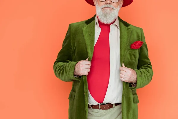 Cropped view of stylish senior man holding jacket isolated on coral — Stock Photo