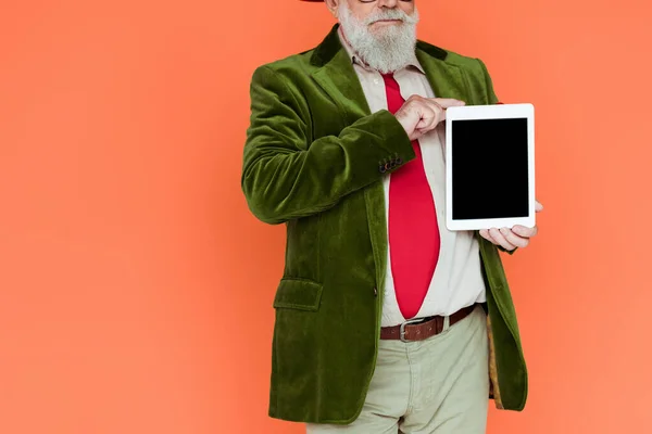 Обрезанный вид стильного пожилого человека с цифровым планшетом с чистым экраном, изолированным на кораллах — стоковое фото