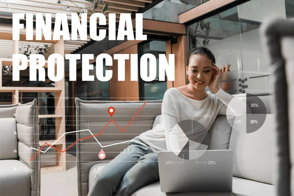 Focalizzazione selettiva di sorridere donna d'affari asiatica seduta sul divano e utilizzando laptop, illustrazione di protezione finanziaria — Foto stock