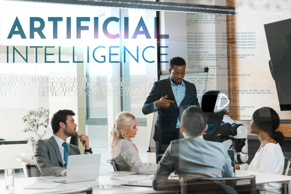 Handsome african american businessman showing robot to multicultural colleagues in office, Artificial Intelligence illustration — Stock Photo