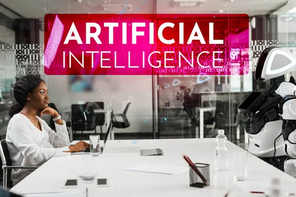 Sorridente Africano americano empresária e robô sentado na mesa na sala de conferências, ilustração Inteligência Artificial — Fotografia de Stock