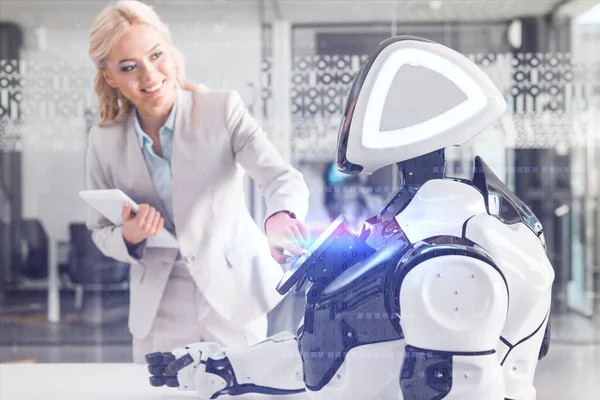 Улыбающаяся деловая женщина, работающая роботом, держа в руках цифровой планшет, кибер иллюстрация — стоковое фото