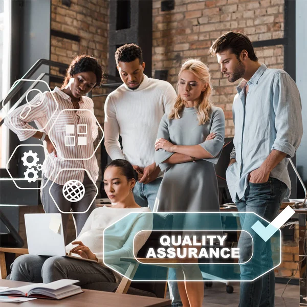 Thoughtful multicultural businesspeople looking at asian colleague working on laptop, quality assurance illustration — Stock Photo