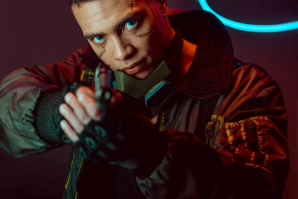 Selektiver Fokus des bewaffneten bi-rassischen Cyberpunk-Spielers mit Waffe auf Schwarz — Stockfoto