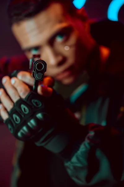 Selective focus of gun in hands of bi-racial cyberpunk player — Stock Photo