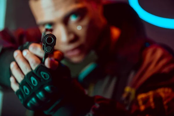 Selective focus of gun in hands of armed bi-racial cyberpunk player — Stock Photo