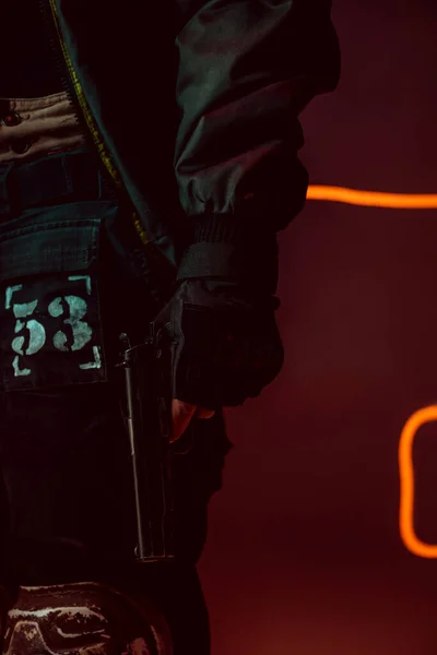 Обрізаний вид кіберпанку з пістолетом на чорному з неоновим освітленням — стокове фото