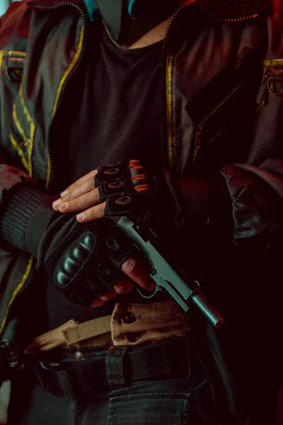 Vue recadrée d'un cyberpunk armé portant des gants tenant un pistolet — Photo de stock