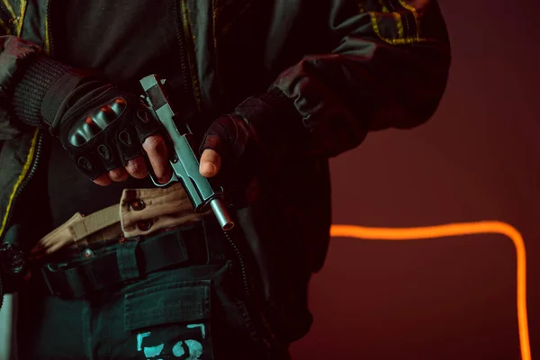 Cropped view of armed cyberpunk player with gun on black with neon lighting — Stock Photo