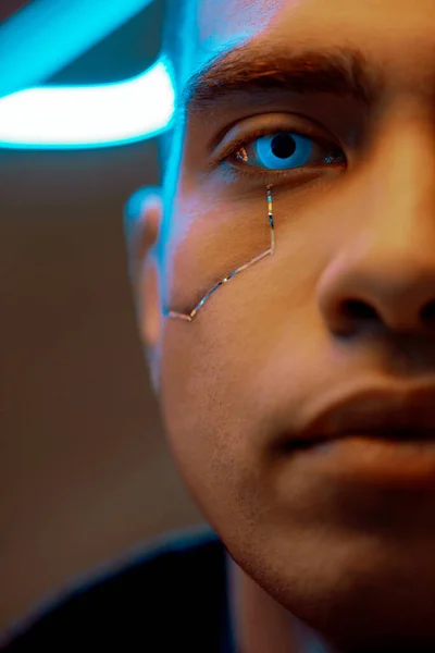 Vista recortada de jugador bi-racial cyberpunk con placas metálicas en la cara y ojos azules mirando a la cámara - foto de stock