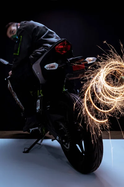 Enfoque selectivo de peligroso jugador cyberpunk raza mixta en la máscara de conducción de motocicleta cerca de chispas en blanco y negro - foto de stock