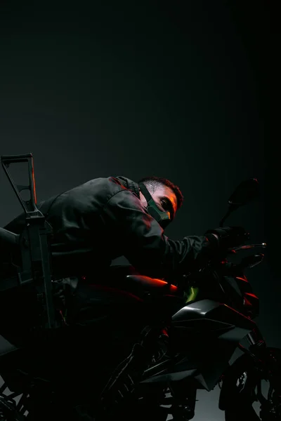 Peligroso jugador cyberpunk raza mixta en la máscara de conducción de motocicleta en gris - foto de stock