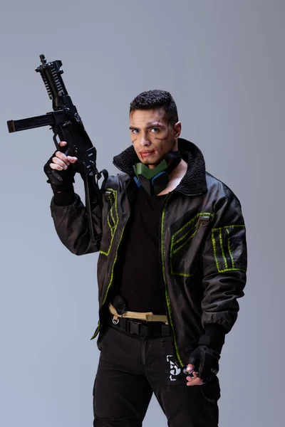 Armed bi-racial cyberpunk player holding gun isolated on grey — Stock Photo