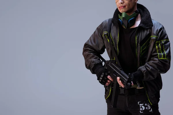 Вид вооруженного киберпанка, держащего в руках пистолет, на сером фоне — стоковое фото
