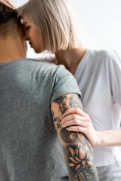 Enfoque selectivo de mujer atractiva tocando novio tatuado aislado en blanco - foto de stock