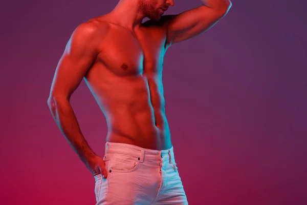 Cropped view of sexy, shirtless man holding hand in back pocket while posing on purple background with gradient — Stock Photo