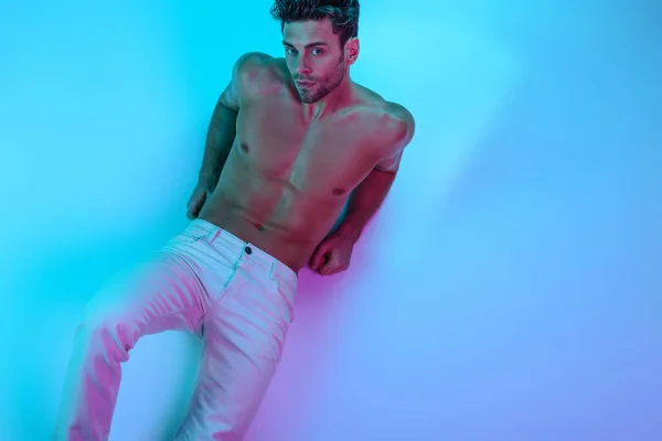 Vista dall'alto di sexy, uomo senza maglietta in jeans bianchi guardando la fotocamera mentre si trova su sfondo blu — Foto stock