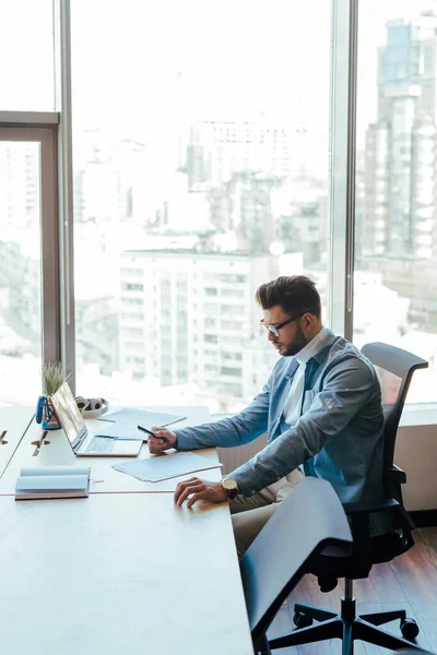 Travailleur informatique avec des papiers à table dans un espace de coworking — Photo de stock