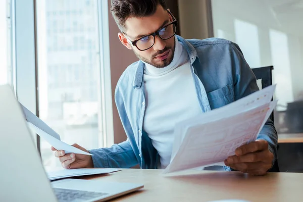 Selective focus of concentrated IT worker with documents at table in coworking space — Stock Photo