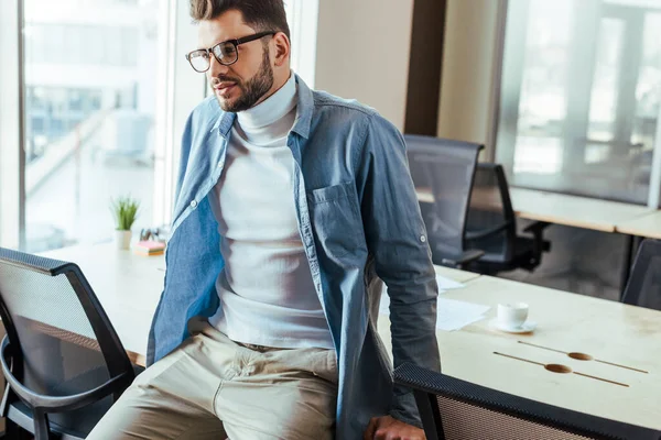 Nachdenklicher IT-Mitarbeiter sitzt im Coworking Space am Tisch — Stockfoto