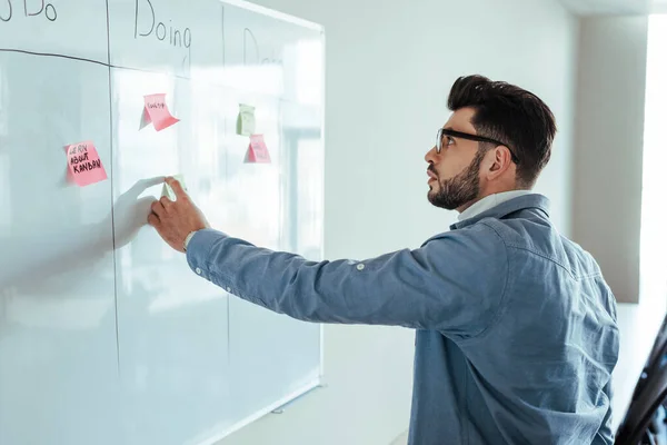 Scrum master looking at white board with spreadsheet and stickers — Stock Photo