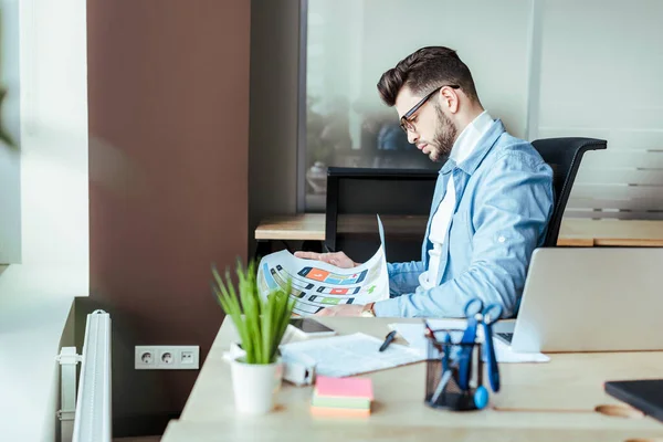 Focus selettivo del progettista UI guardando carta tessuta a tavola — Foto stock