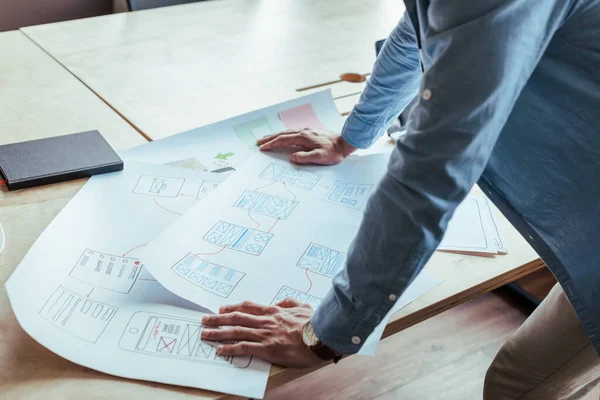 Partial view of UI designer with wove papers and notebook at table — Stock Photo