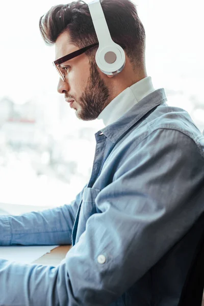 Side view of concentrated IT worker in glasses with headphones — Stock Photo