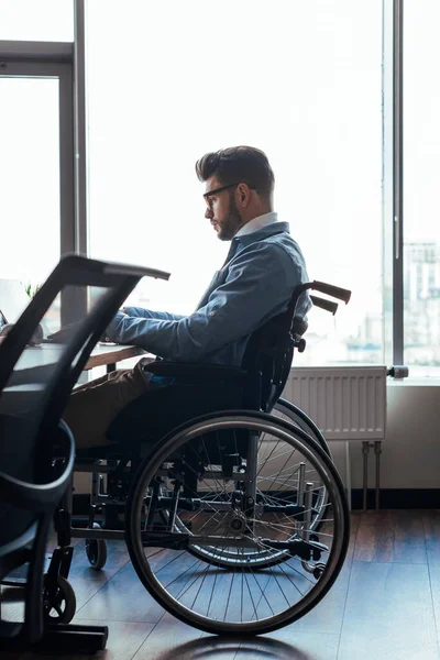 Selective focus of concentrated disabled IT worker on wheelchair working in coworking space — Stock Photo