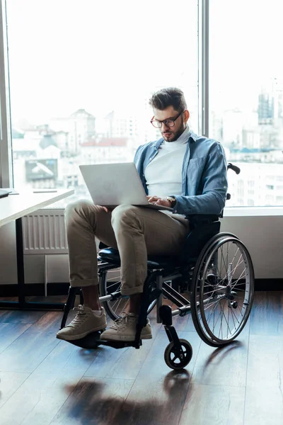 Disabled IT worker on wheelchair working with laptop on wheelchair in coworking space — Stock Photo