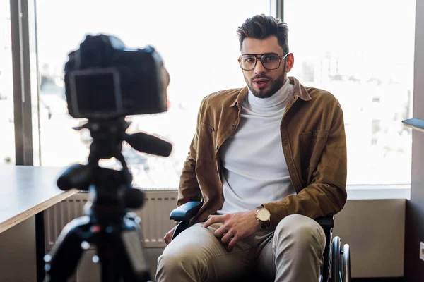 Selective focus of disabled blogger on wheelchair talking in front of digital camera — Stock Photo