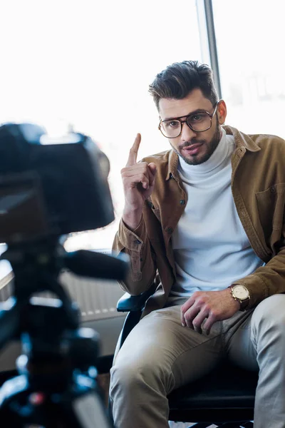 Вибірковий фокус вимкненого блогера, який вказує пальцем і розмовляє перед цифровою камерою — стокове фото