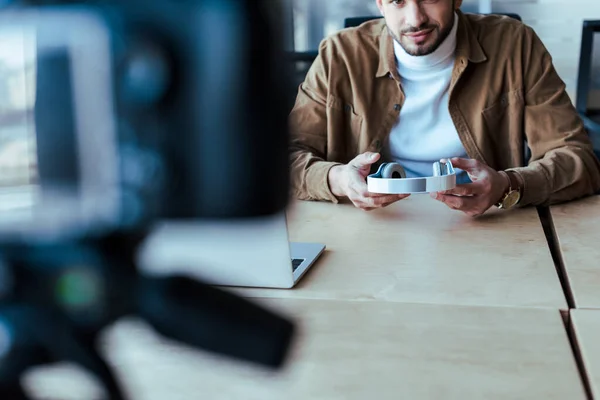 Vista ritagliata del blogger che tiene le cuffie a tavola — Foto stock