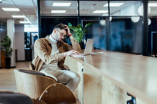 Foco seletivo do trabalhador de TI concentrado usando laptop à mesa no espaço de coworking — Fotografia de Stock