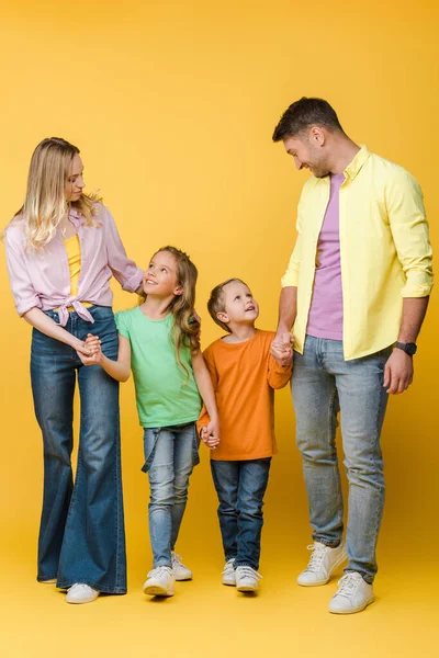 Glückliche Familie hält Händchen mit Kindern auf gelb — Stockfoto